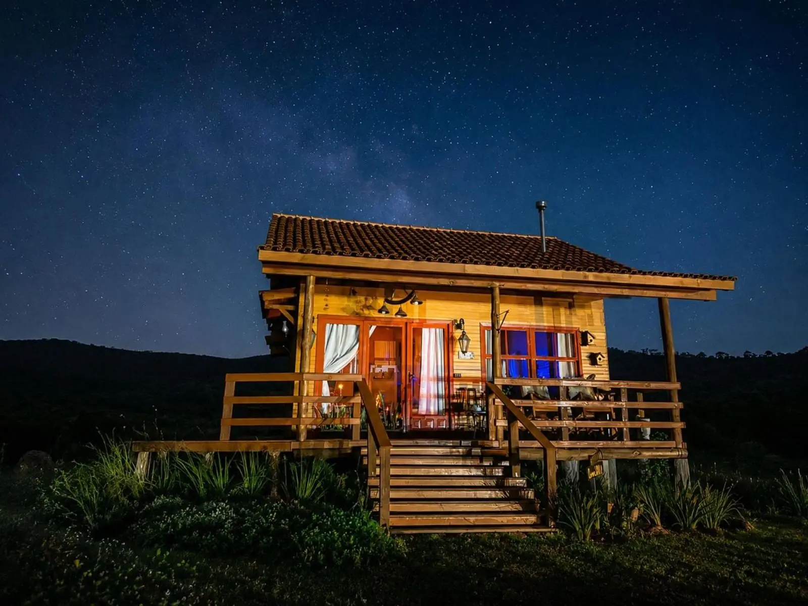 Cabana Gaia iluminada sob o céu estrelado